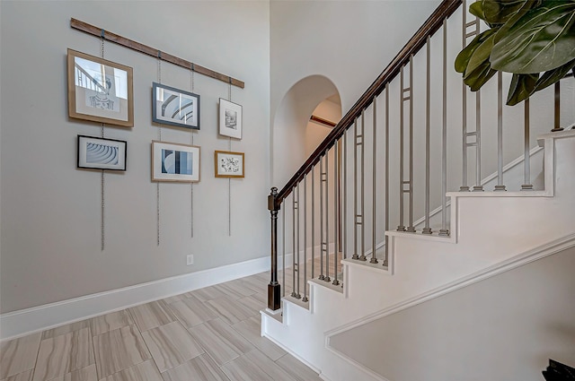 stairway with arched walkways and baseboards