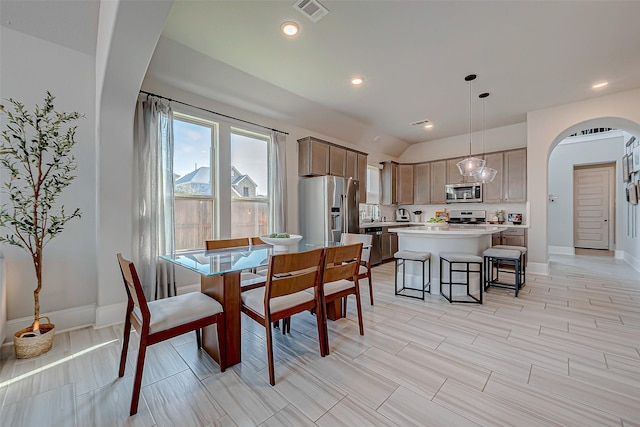 dining space featuring arched walkways, lofted ceiling, visible vents, and baseboards