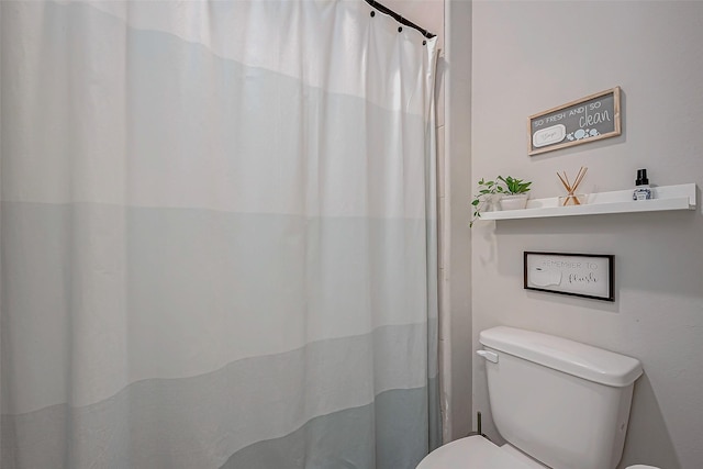 bathroom featuring toilet and curtained shower