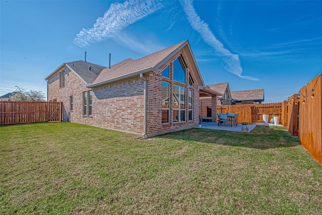 back of property with brick siding, a patio, a fenced backyard, and a lawn