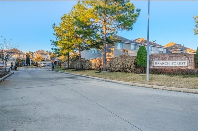 view of street featuring a residential view, a gated entry, and curbs