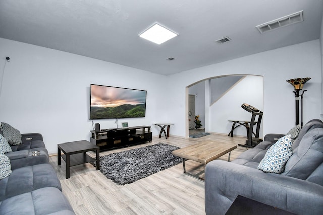 living room featuring arched walkways, visible vents, and wood finished floors