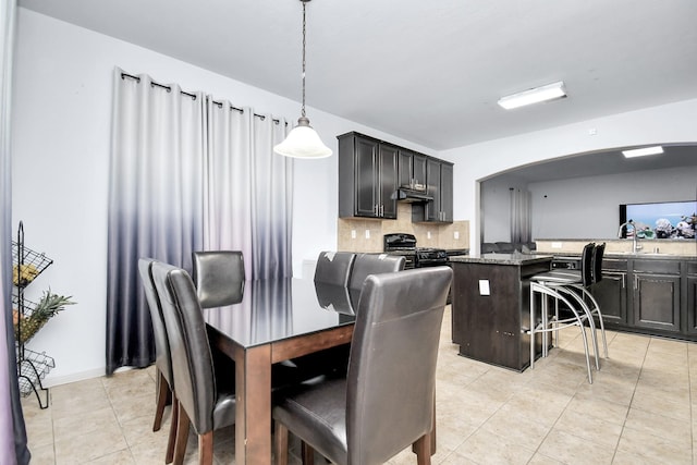 dining room featuring light tile patterned floors, arched walkways, and baseboards