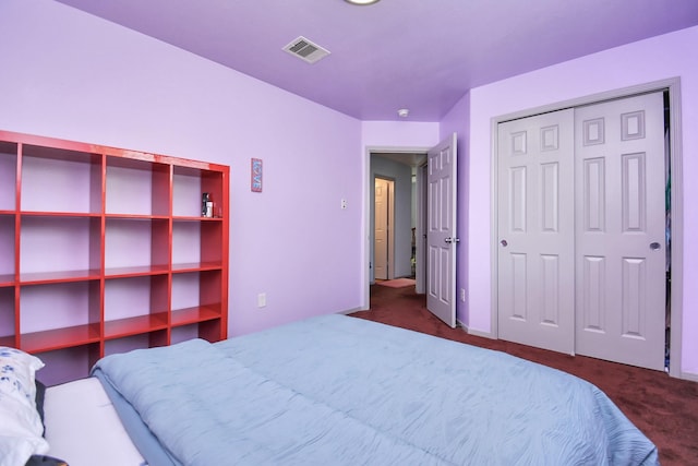 bedroom featuring visible vents, dark carpet, and a closet