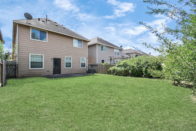 back of property with central air condition unit, a fenced backyard, and a lawn