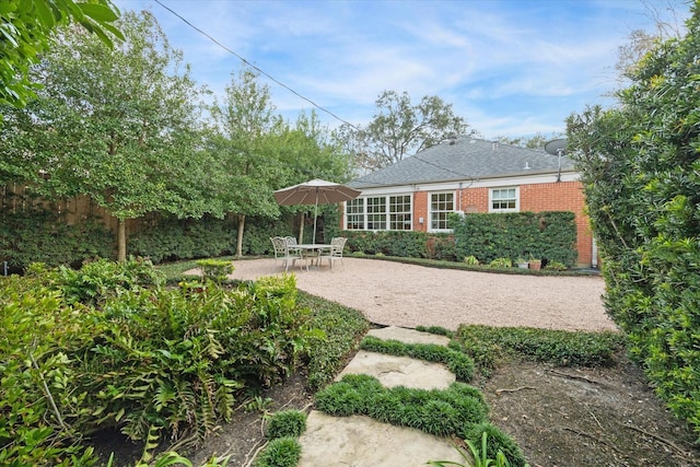 back of property with roof with shingles, fence, a patio, and brick siding