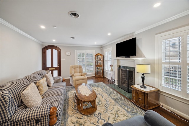 living room with a premium fireplace, wood finished floors, visible vents, baseboards, and ornamental molding