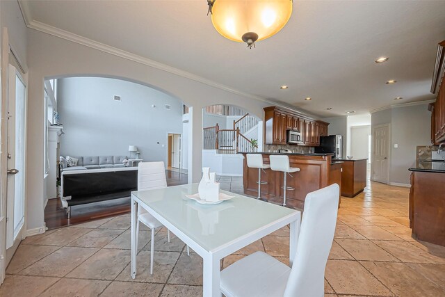 dining room with arched walkways, crown molding, recessed lighting, stairway, and baseboards