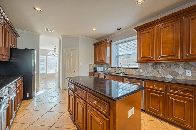 kitchen featuring tasteful backsplash, visible vents, a center island, crown molding, and a sink