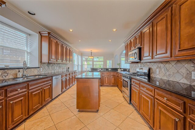 kitchen with appliances with stainless steel finishes, crown molding, a sink, and decorative backsplash