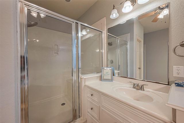 bathroom featuring ceiling fan, a shower stall, and vanity