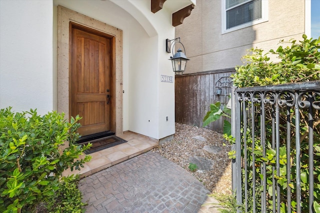 property entrance featuring fence and stucco siding