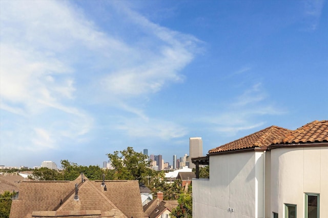 exterior space with a tiled roof, stucco siding, and a city view