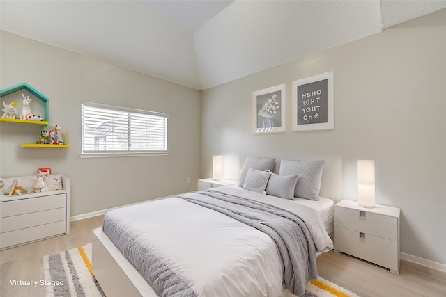 bedroom featuring light wood-style floors, vaulted ceiling, and baseboards