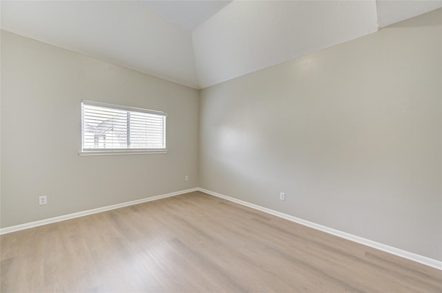 unfurnished room with light wood-style flooring, baseboards, and vaulted ceiling