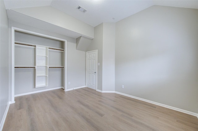 unfurnished bedroom with lofted ceiling, visible vents, baseboards, and wood finished floors