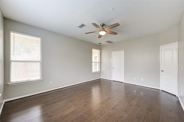 unfurnished room with ceiling fan, dark wood-type flooring, visible vents, and baseboards