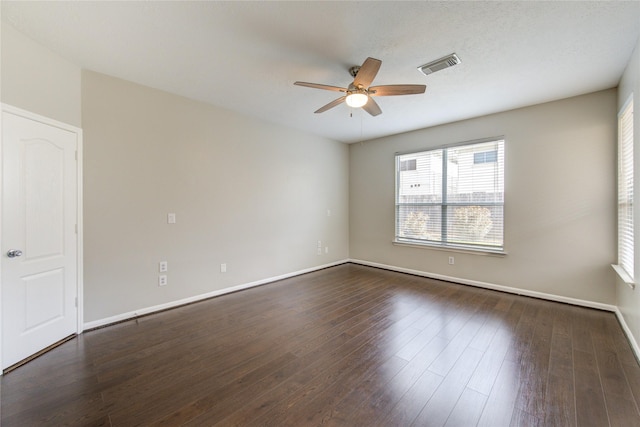 unfurnished room featuring ceiling fan, visible vents, dark wood finished floors, and baseboards