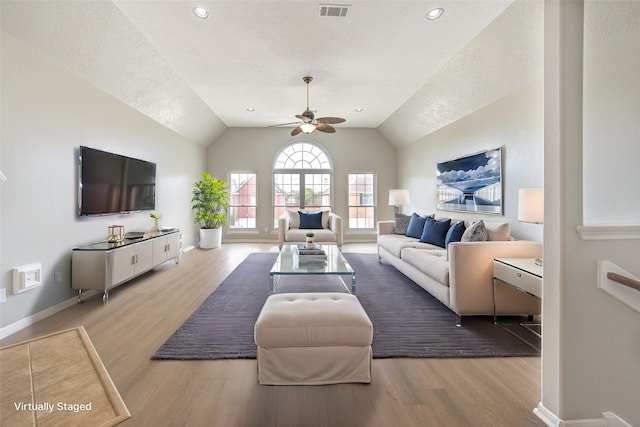 living room with ceiling fan, wood finished floors, visible vents, baseboards, and vaulted ceiling