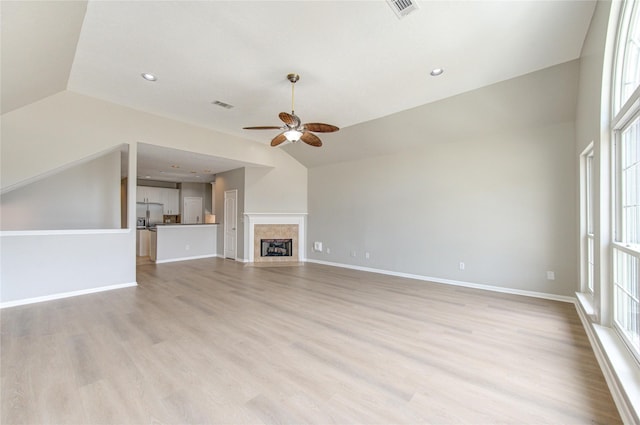 unfurnished living room with visible vents, a fireplace with flush hearth, vaulted ceiling, light wood-type flooring, and baseboards