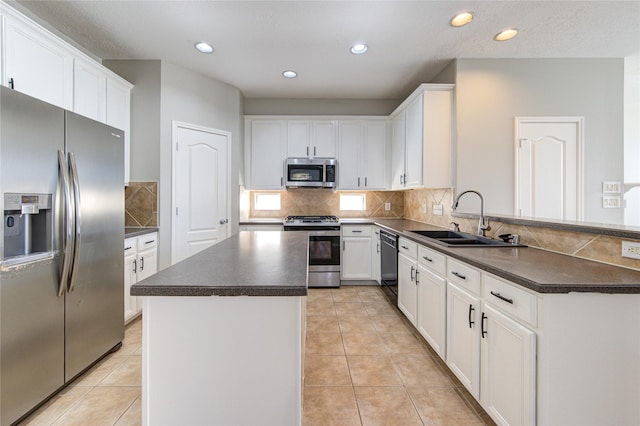 kitchen with stainless steel appliances, dark countertops, a sink, and a peninsula