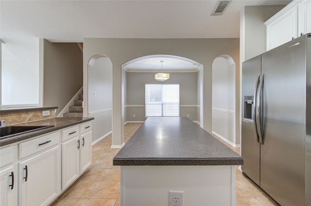 kitchen featuring dark countertops, light tile patterned floors, white cabinets, and stainless steel refrigerator with ice dispenser