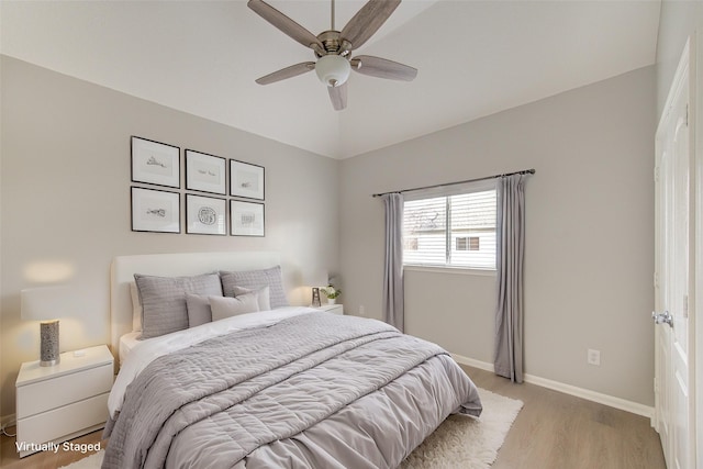 bedroom with a ceiling fan, vaulted ceiling, light wood-style flooring, and baseboards