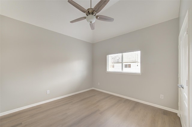 empty room with light wood-style floors, ceiling fan, baseboards, and vaulted ceiling