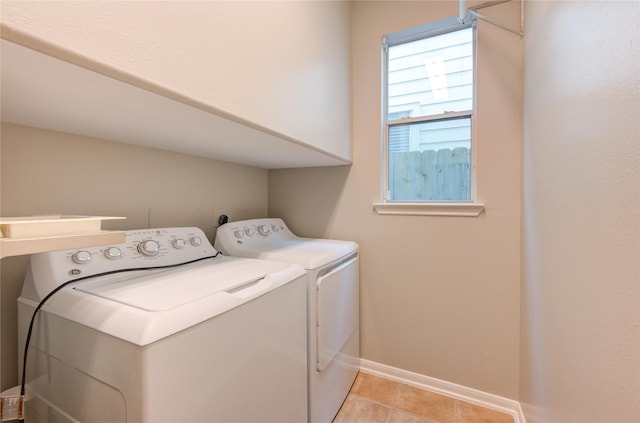 clothes washing area featuring baseboards, washer and clothes dryer, and light tile patterned flooring