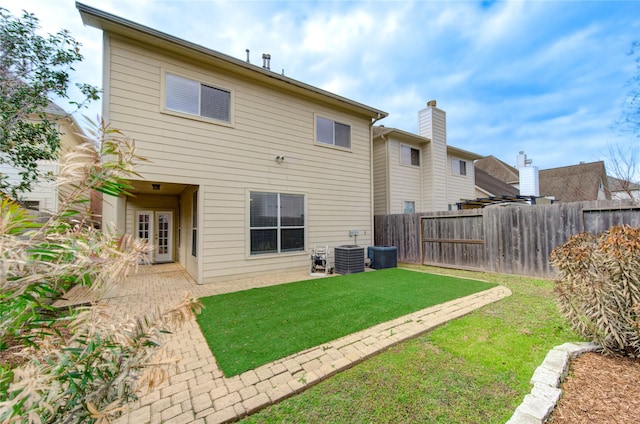 rear view of house with central air condition unit, fence private yard, a patio area, and a yard