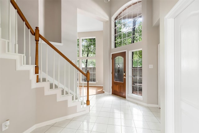 entryway with tile patterned floors, baseboards, a towering ceiling, and stairs