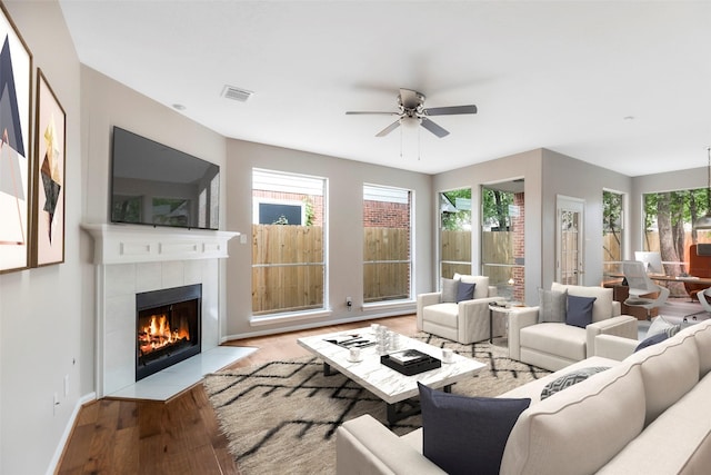 living room featuring visible vents, a healthy amount of sunlight, a tile fireplace, and wood finished floors