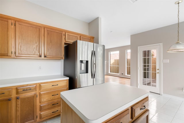 kitchen with brown cabinets, pendant lighting, a center island, stainless steel fridge with ice dispenser, and light countertops