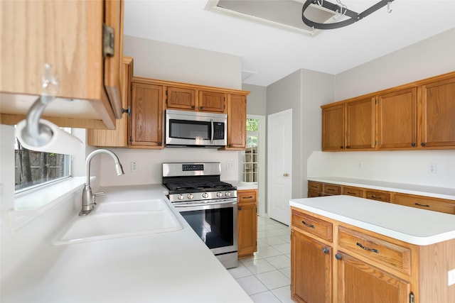 kitchen with light tile patterned flooring, a sink, light countertops, appliances with stainless steel finishes, and brown cabinets