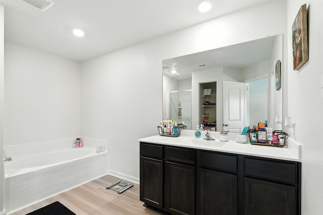 22052 Angelico Dr, Magnolia, TX 77355 - full bath featuring vanity, wood finished floors, a bath, and recessed lighting