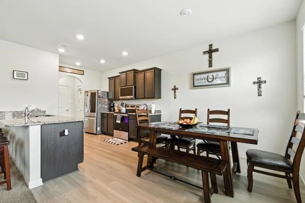 22052 Angelico Dr, Magnolia, TX 77355 - dining area featuring light wood finished floors, arched walkways, and recessed lighting