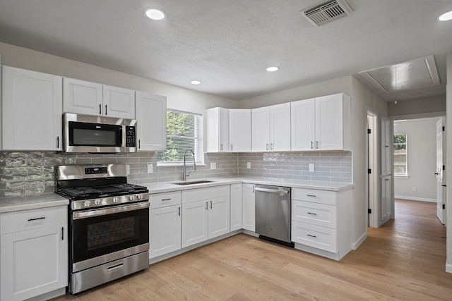 kitchen with light wood-style flooring, a sink, visible vents, light countertops, and appliances with stainless steel finishes