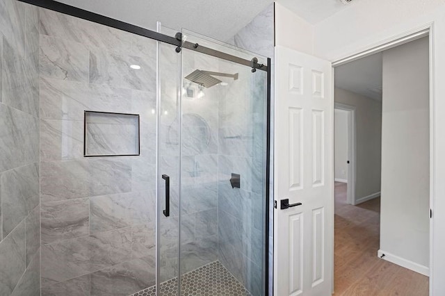 bathroom featuring a stall shower, wood finished floors, and baseboards