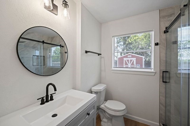 bathroom with toilet, a stall shower, baseboards, and vanity