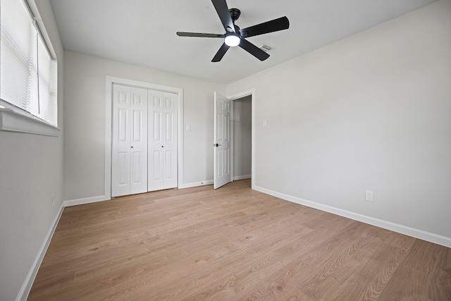 unfurnished bedroom featuring baseboards, ceiling fan, a closet, and light wood-style floors