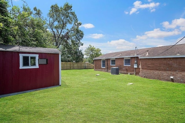 view of yard with an outbuilding, fence, and central air condition unit