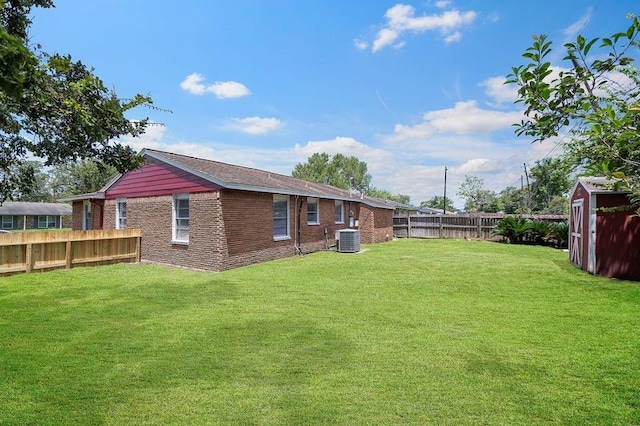 view of yard featuring a fenced backyard, an outdoor structure, a storage unit, and central AC unit