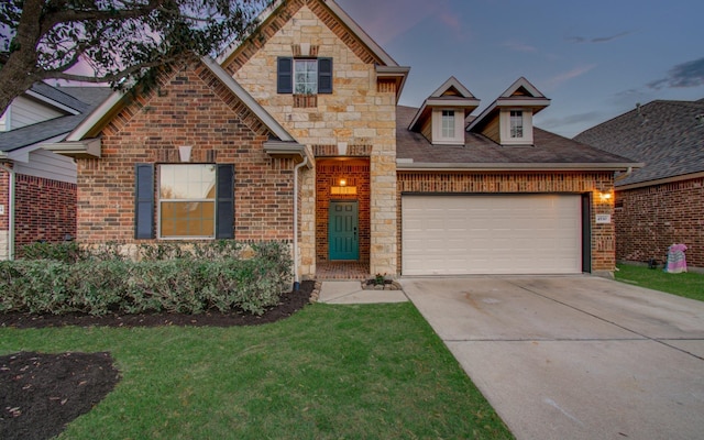 view of front of house with an attached garage, concrete driveway, a front lawn, stone siding, and brick siding