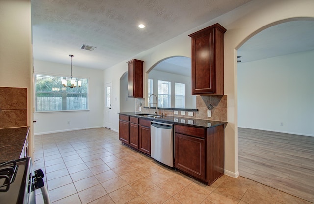 kitchen featuring dishwasher, visible vents, arched walkways, and a sink