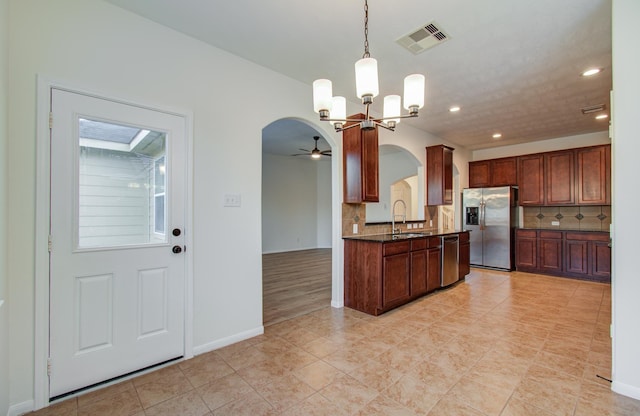 kitchen featuring visible vents, arched walkways, appliances with stainless steel finishes, ceiling fan with notable chandelier, and backsplash