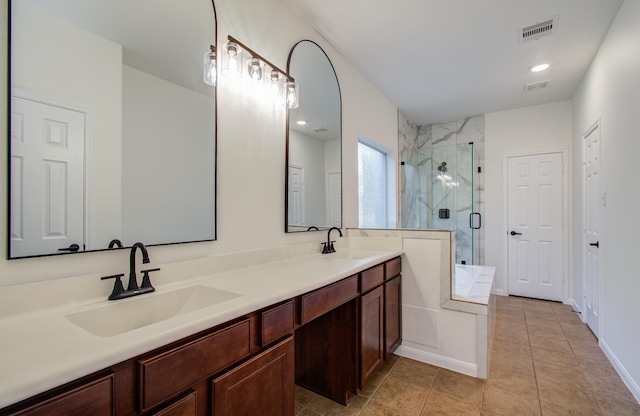 full bathroom with double vanity, visible vents, a stall shower, and a sink