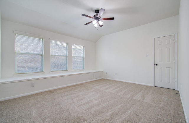 spare room featuring baseboards, light colored carpet, a ceiling fan, and vaulted ceiling