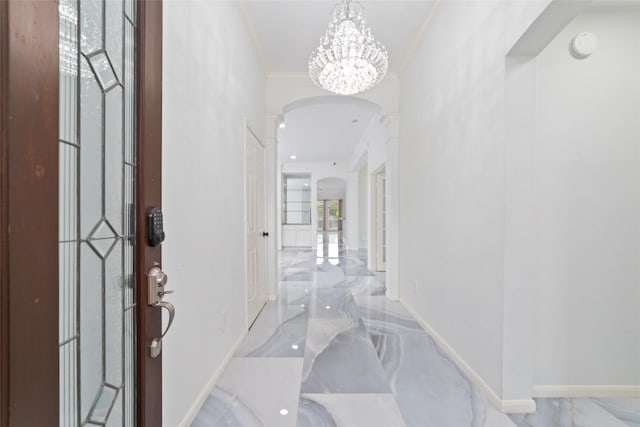 entryway featuring arched walkways, a notable chandelier, baseboards, marble finish floor, and ornamental molding