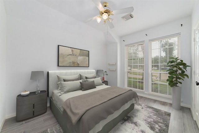 bedroom featuring light wood finished floors, baseboards, visible vents, and a ceiling fan