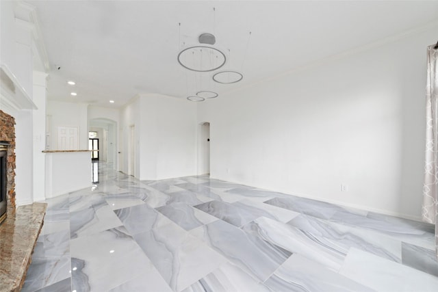 living area with arched walkways, marble finish floor, a stone fireplace, and recessed lighting